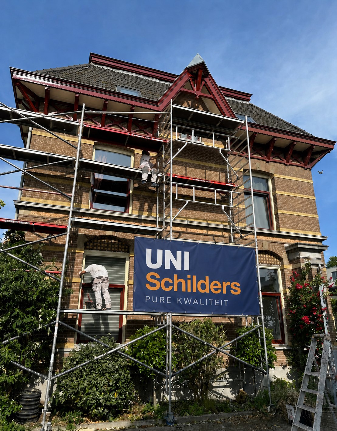 UniSchilders schilder op steiger bezig met buitenschilderwerk aan woning